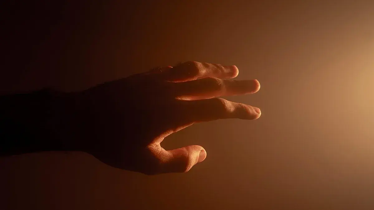 Mão estendida em ambiente escuro sob luz quente, representando queimação nas mãos à noite
