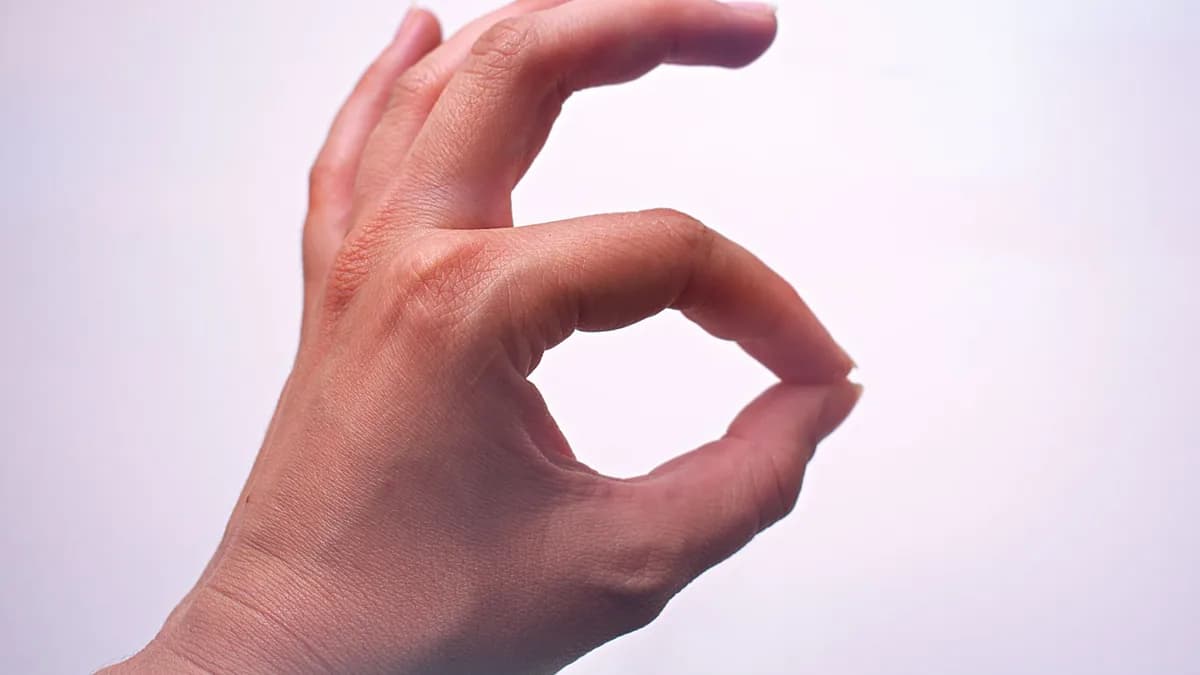 Mão fazendo o gesto de OK com o dedo indicador em destaque